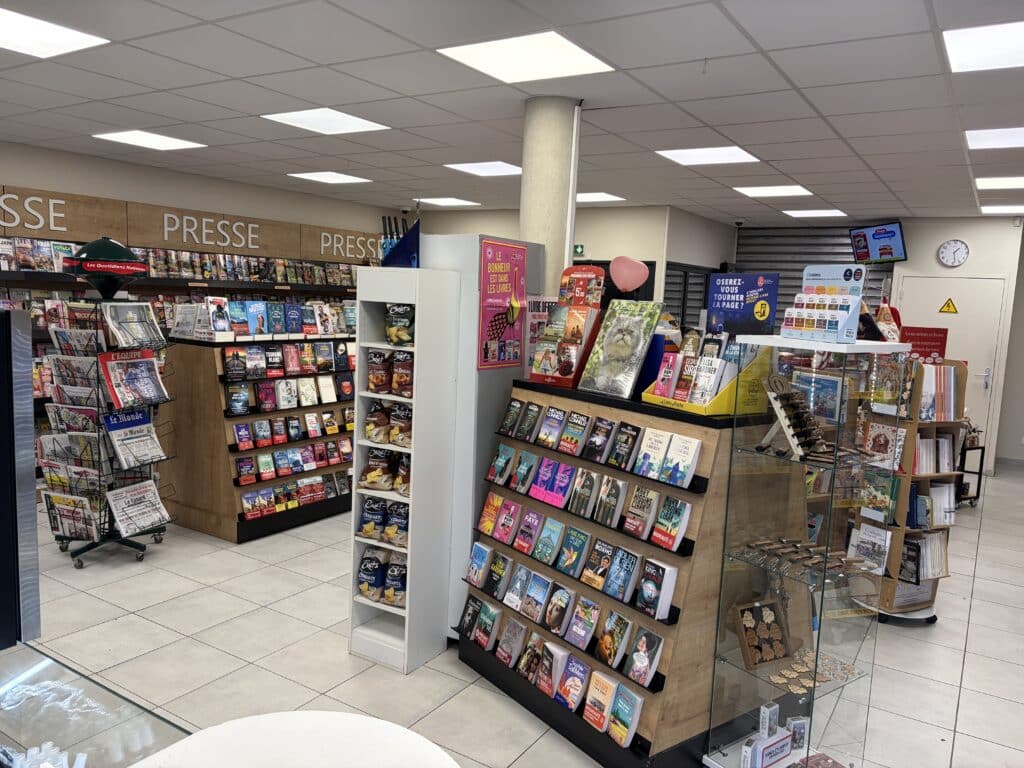 Librairie-Presse : Rayonnages de Livres et Magazines Rayonnages de livres et magazines dans une librairie-presse française affichant Le bonheur est dans les livres.