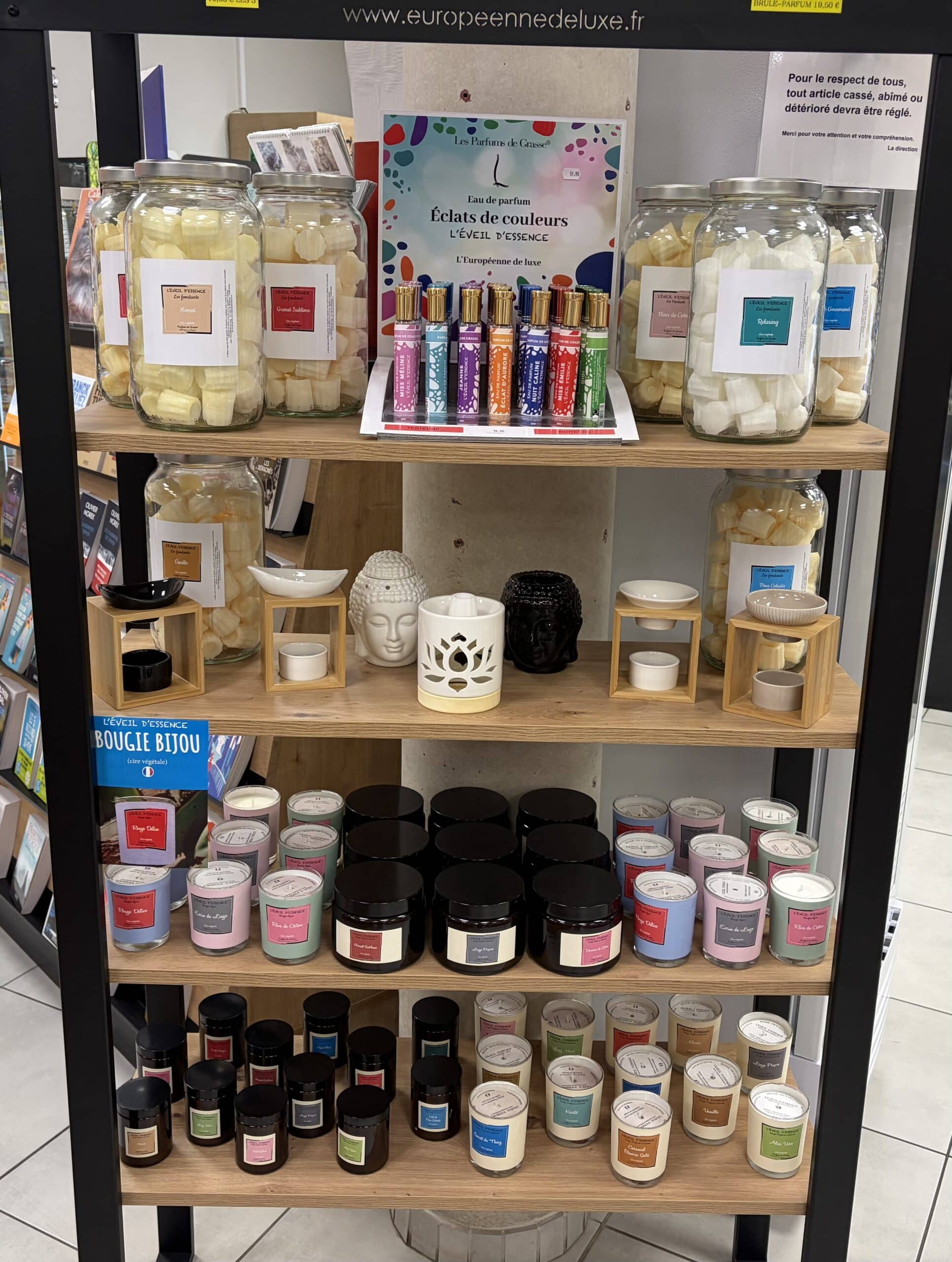 Étagère L'Éveil d'Essence : bougies bijoux, parfums de Grasse et diffuseurs en céramique exposés en magasin.