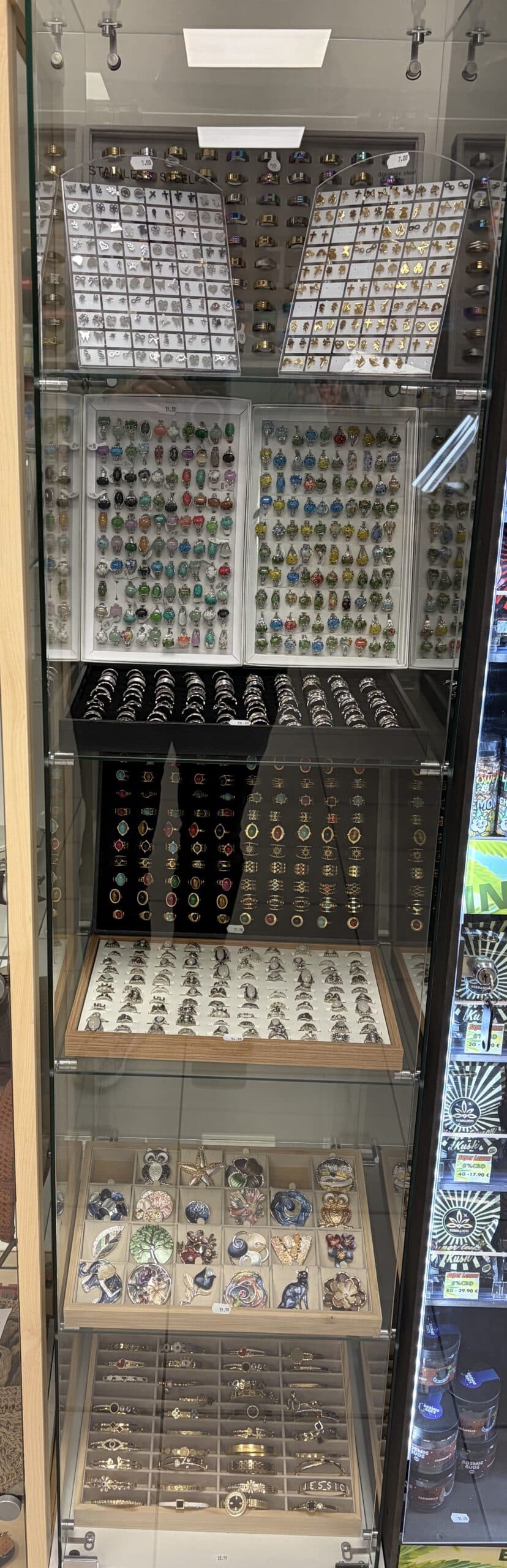 Vitrine de bijoux exposant une large sélection de bagues, bracelets et broches fantaisie colorées.