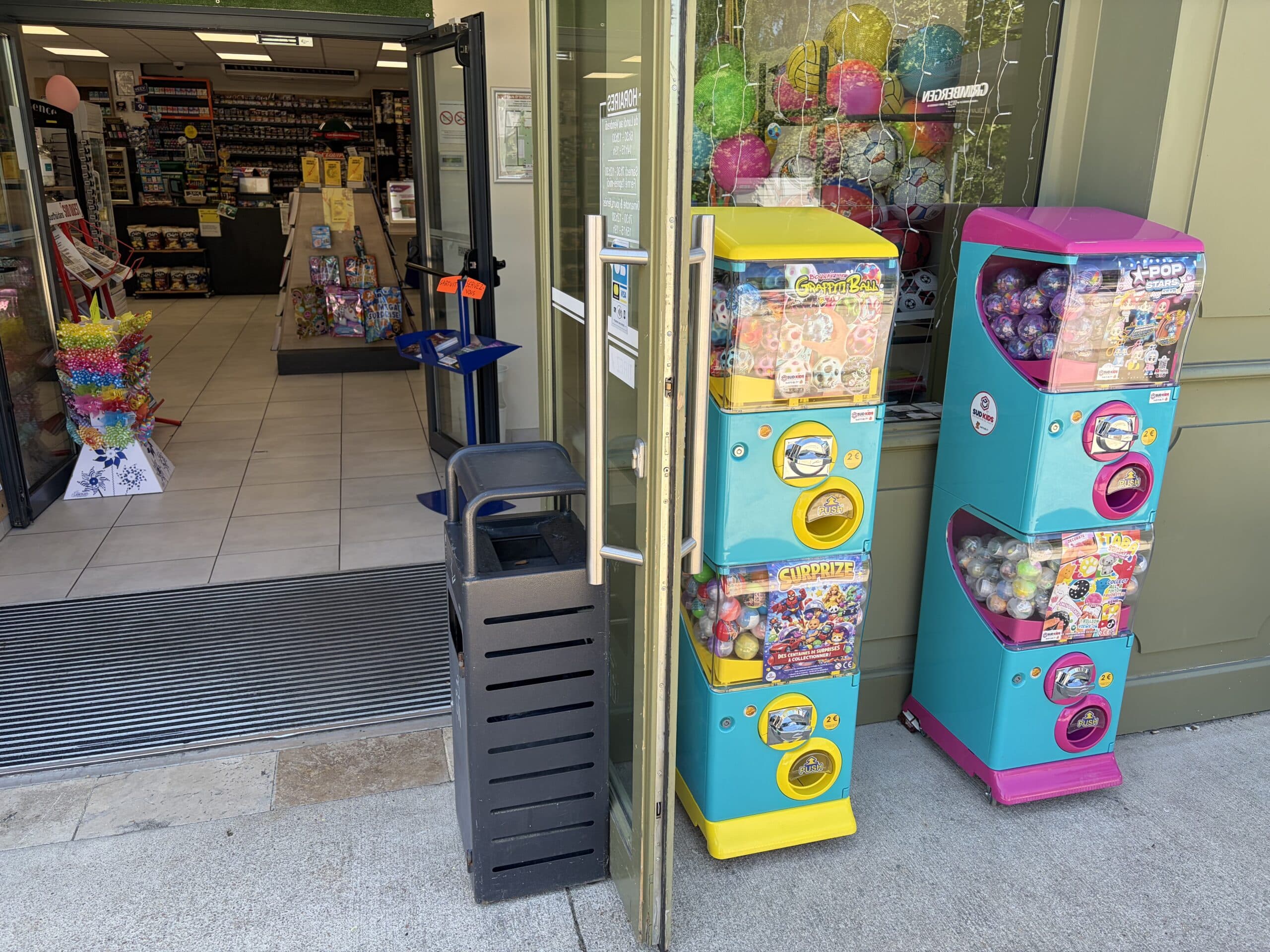 Distributeurs de capsules SUD KIDS devant un magasin de presse proposant Graffiti Ball et Surprise à 2€.